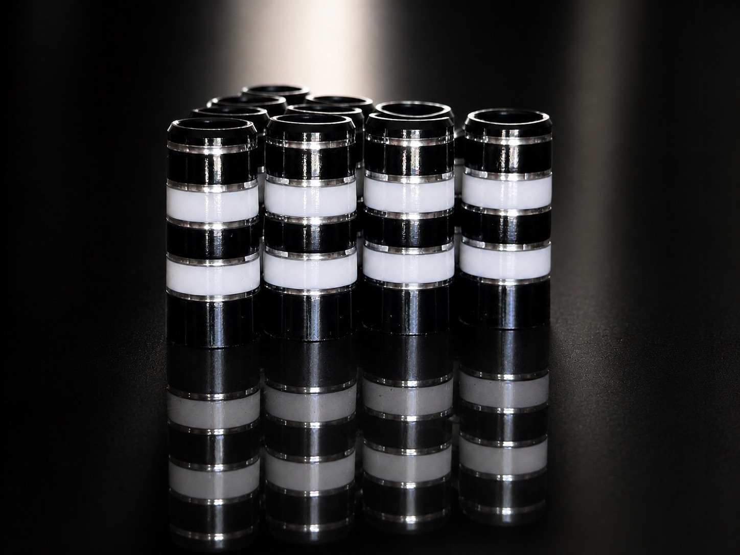 A pack of ten Classy Jailbird ferrules: glossy black with white bands and polished silver pinstripes, standing on a mirrored black surface.